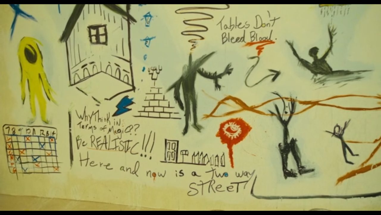 Mural text: Tables Don’t Bleed Blood, Be REALISTIC, Here and now is a two way street