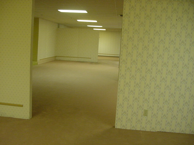 An empty furniture store with yellow walls and fluorescent lights